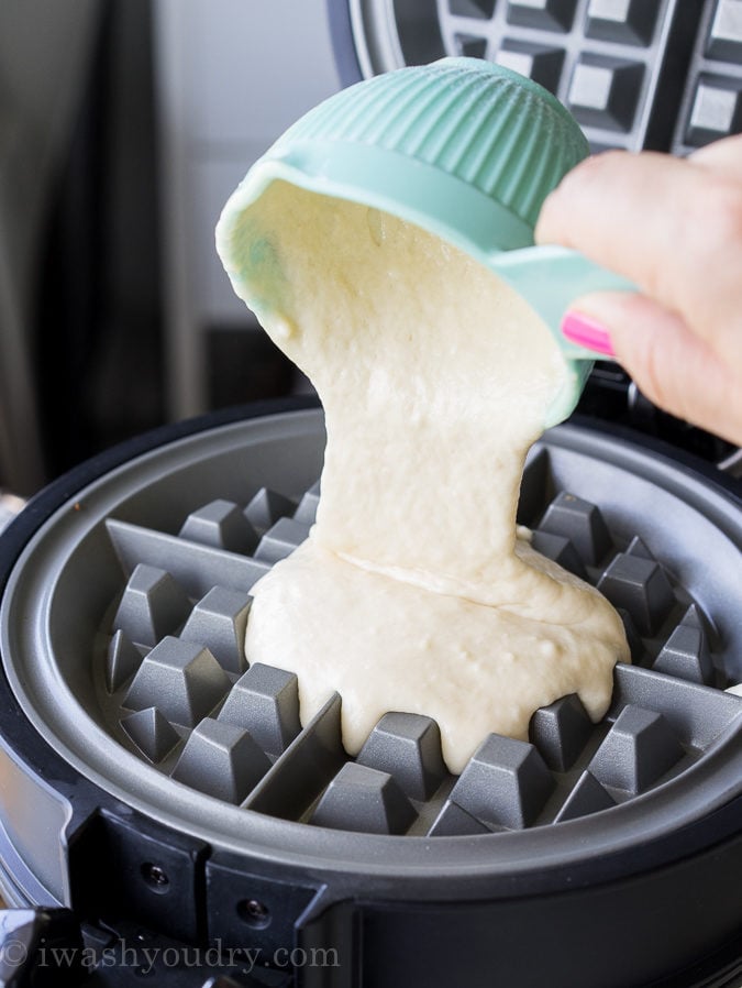 Pouring classic waffle recipe batter into a hot waffle iron.