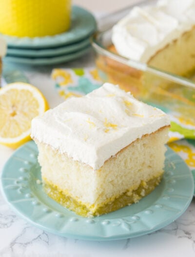A square of lemon cake on a plate with white frosting