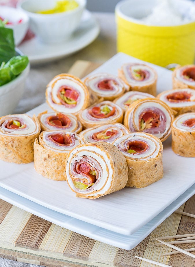platter full of wrapped pinwheel sandwiches with toothpicks