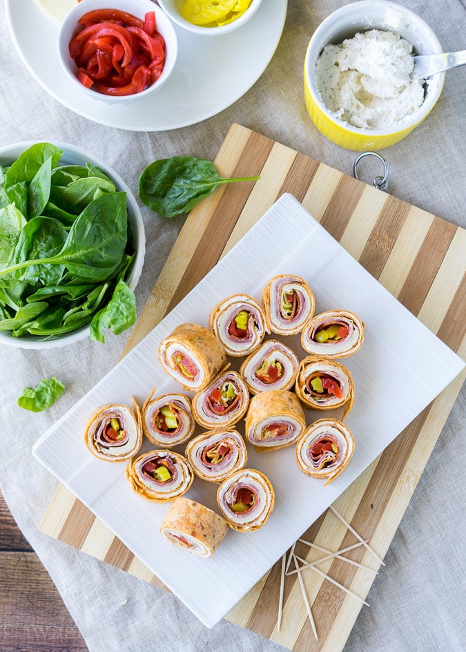 Tray of pinwheels with ingredients surrounding it