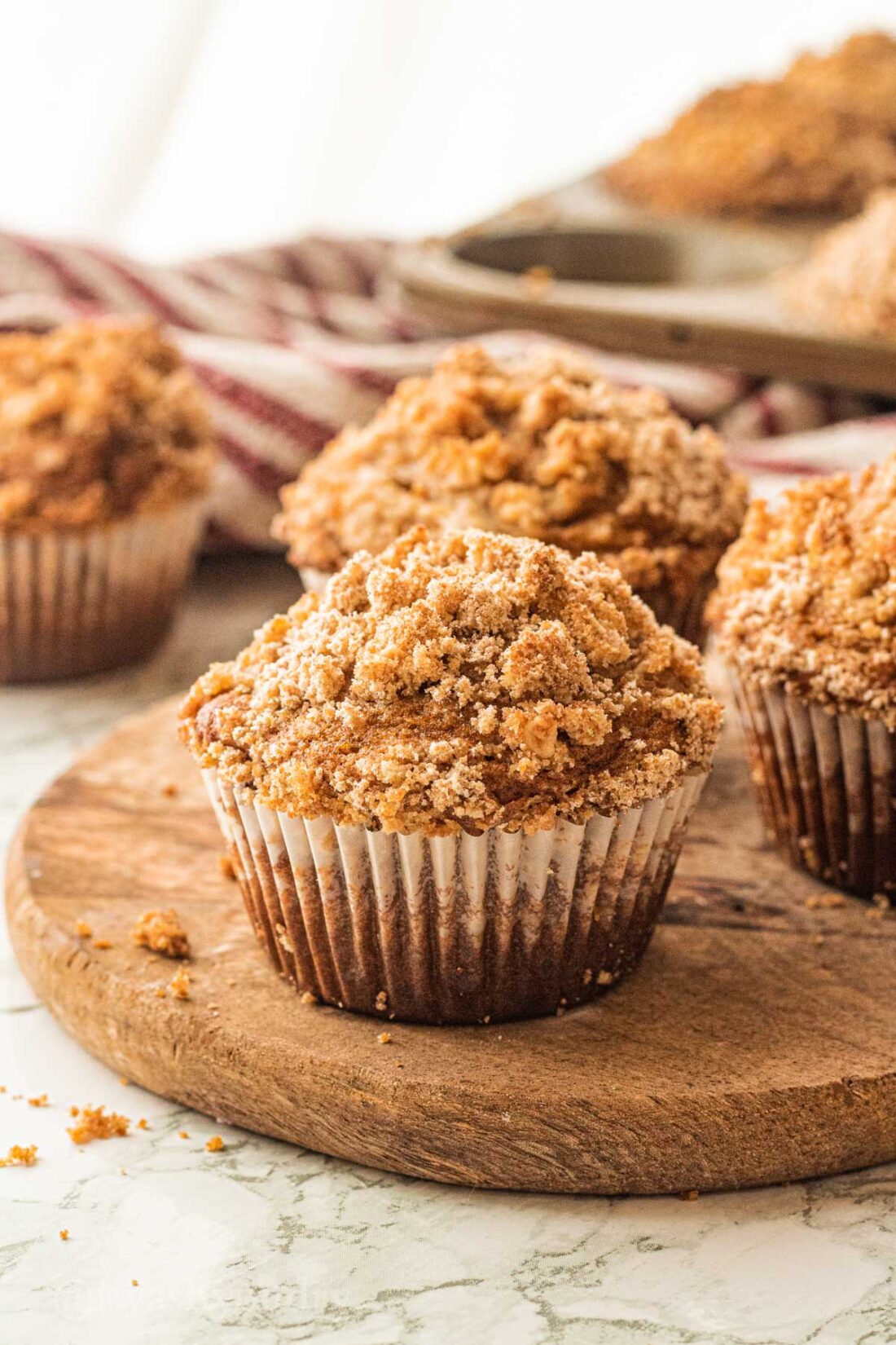 pumpkin crumb muffin on wooden platter with crumbs next to it.