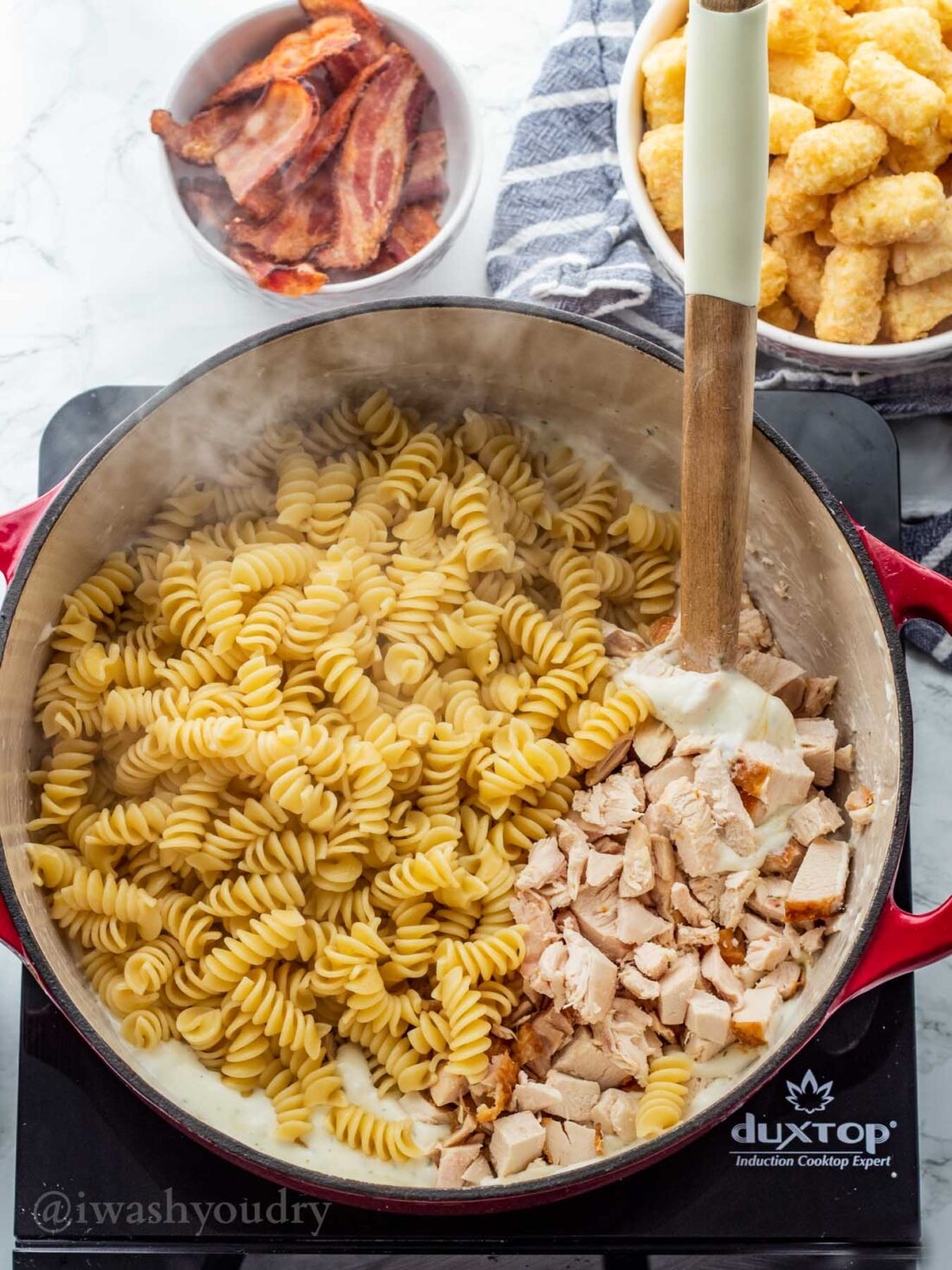 Cooked pasta and chicken in ranch alfredo sauce in large cooking pot. 