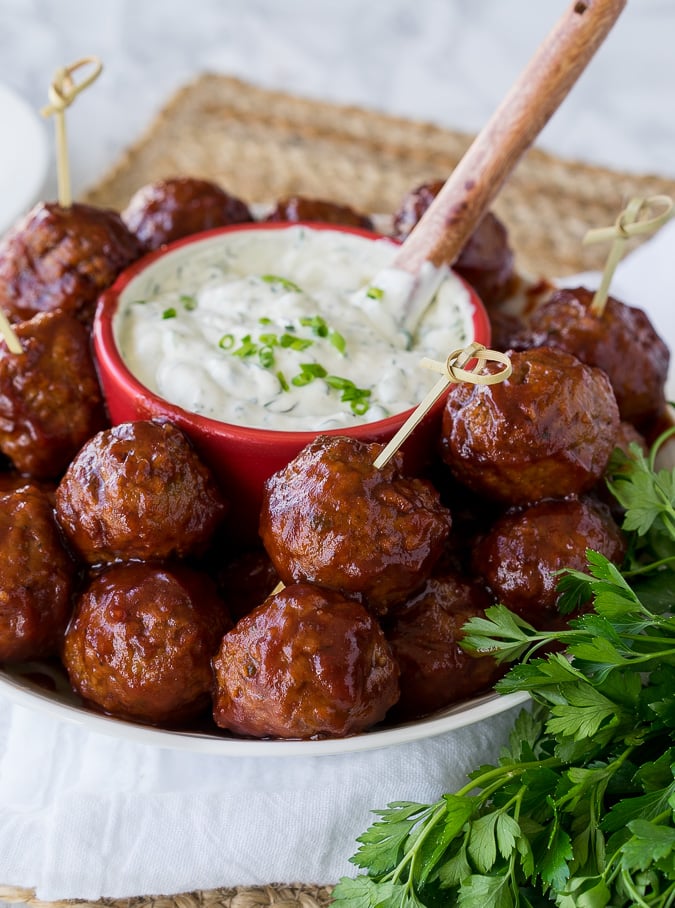 Bowl filled with meatballs and dip in center.