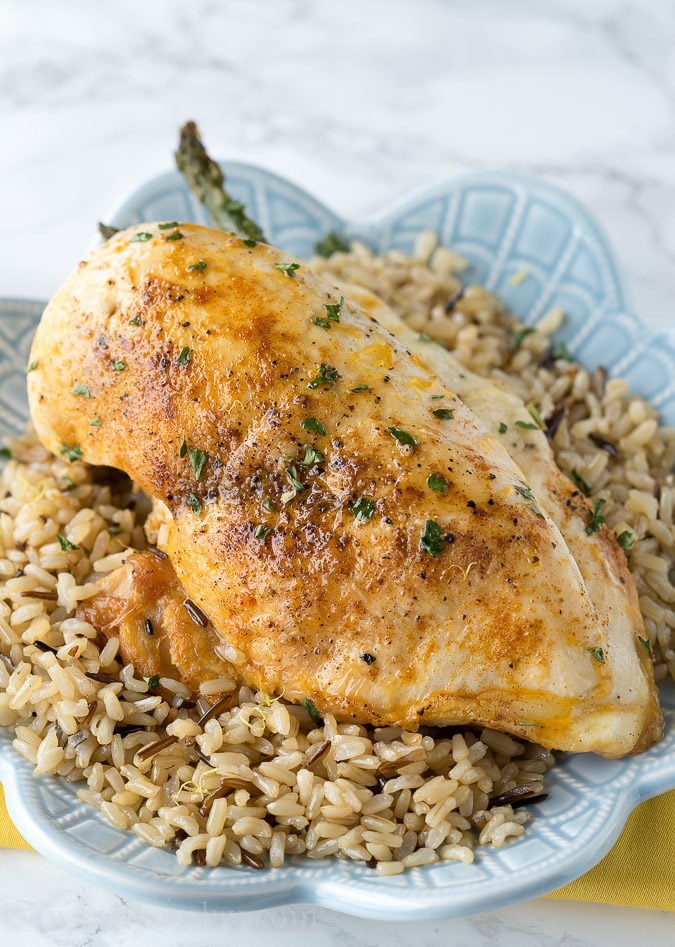 Juicy baked chicken breast stuffed with asparagus and cheese on top of rice.