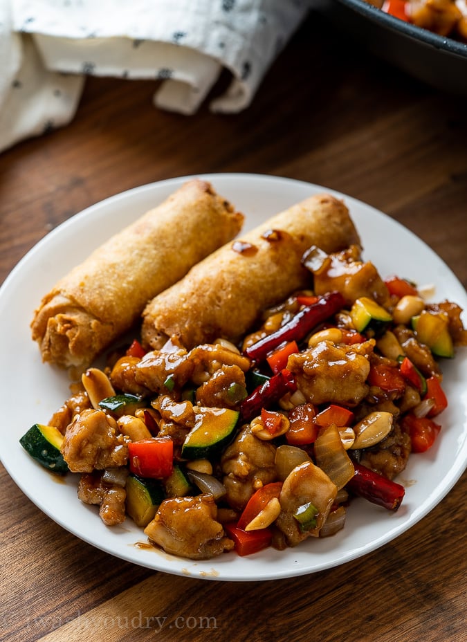 chinese kung pao chicken with egg rolls on plate