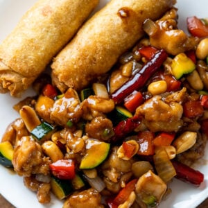 chicken and zucchini in sauce with egg rolls on white plate