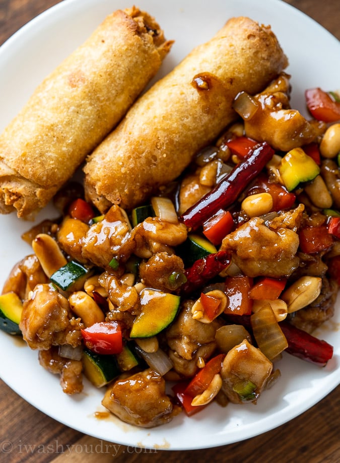 chicken and zucchini in sauce with egg rolls on white plate