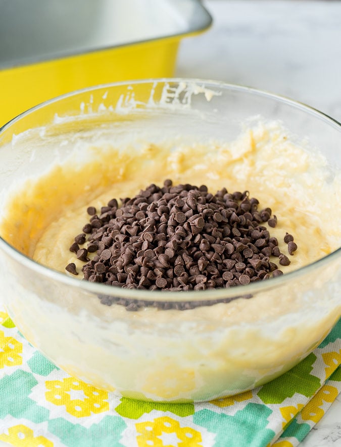 Banana bread batter in a large bowl with chocolate chips on top, ready to be mixed.