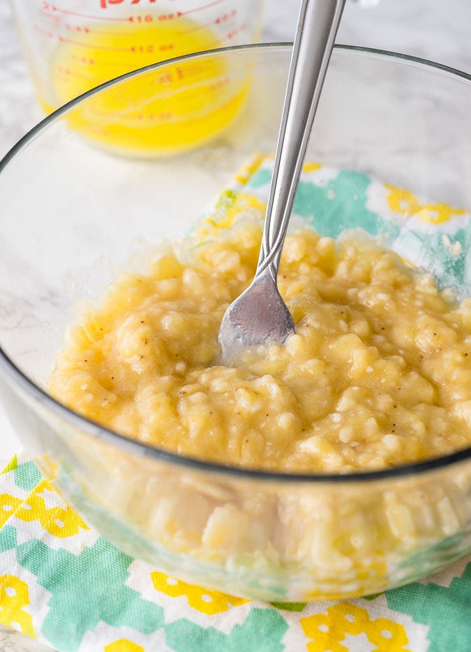 To make homemade banana bread, start by mashing up ripe bananas in a bowl with a fork. No mixer needed!