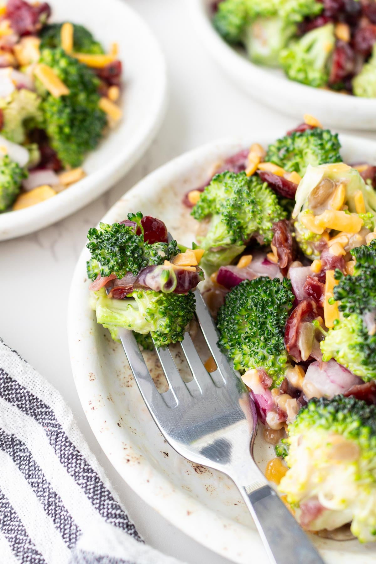 forkful of broccoli salad on plate.