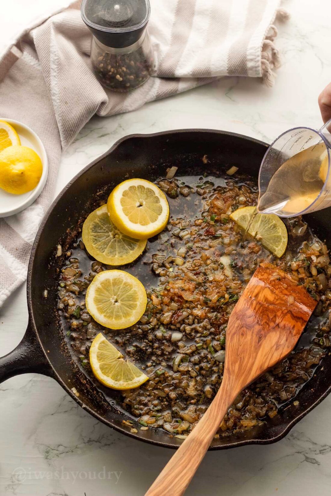 pouring in white wine and lemons to create pan sauce.