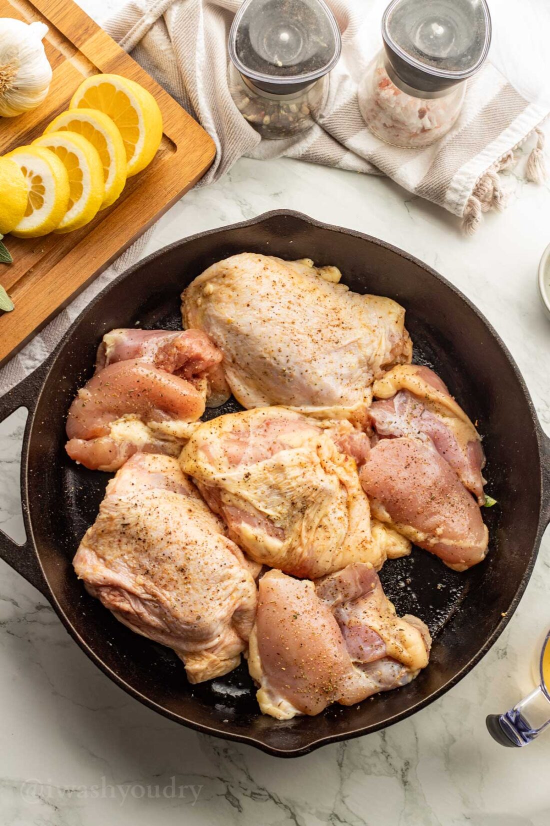cooking chicken thighs in a large black pan.