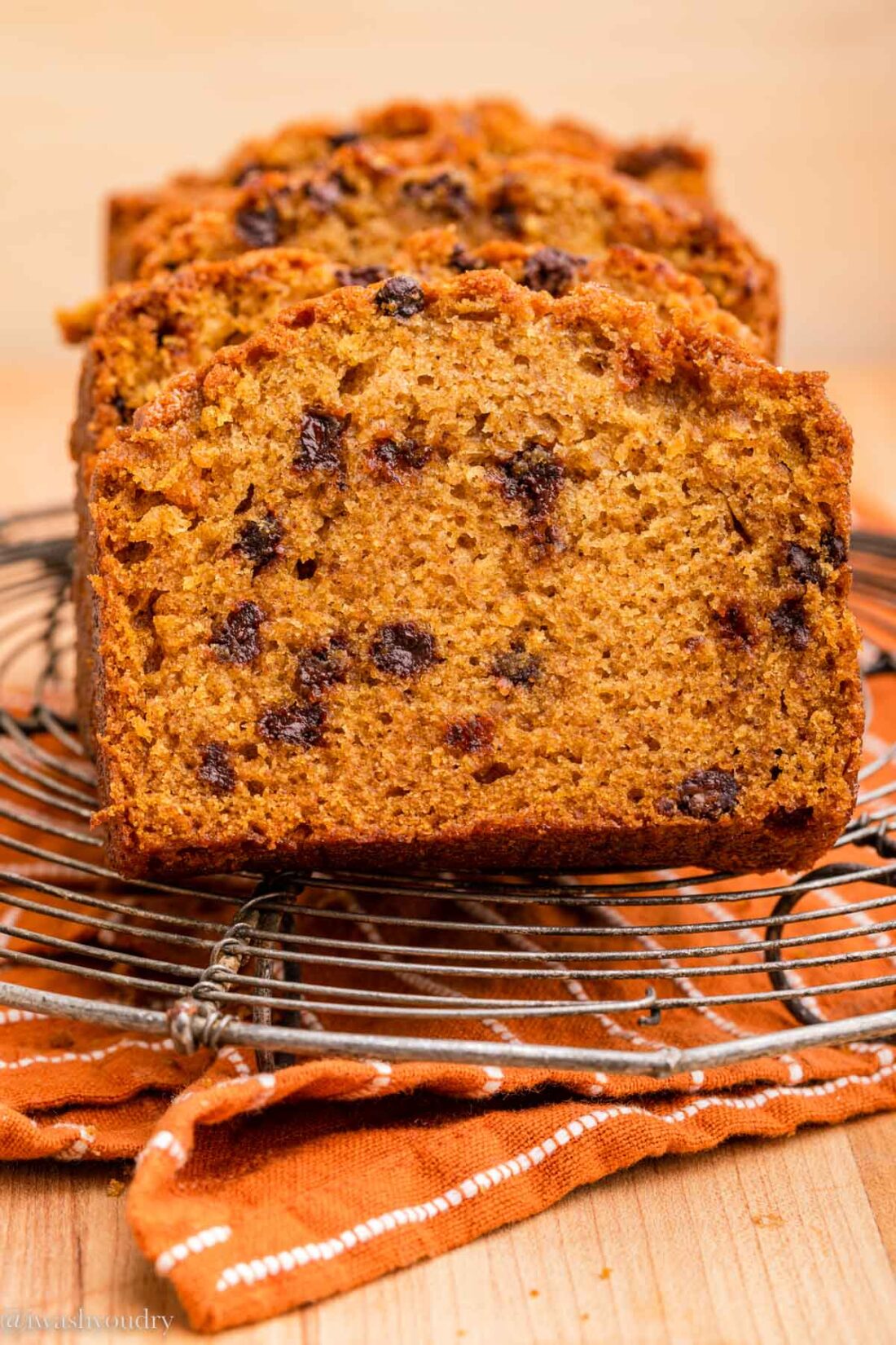 sliced of baked pumpkin chocolate chip bread on metal cooling rack with dishtowel. 
