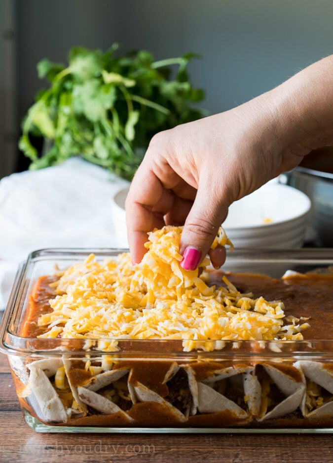 Top the ground beef enchiladas with generous amounts of shredded cheddar cheese and then bake until bubbly and heated through!