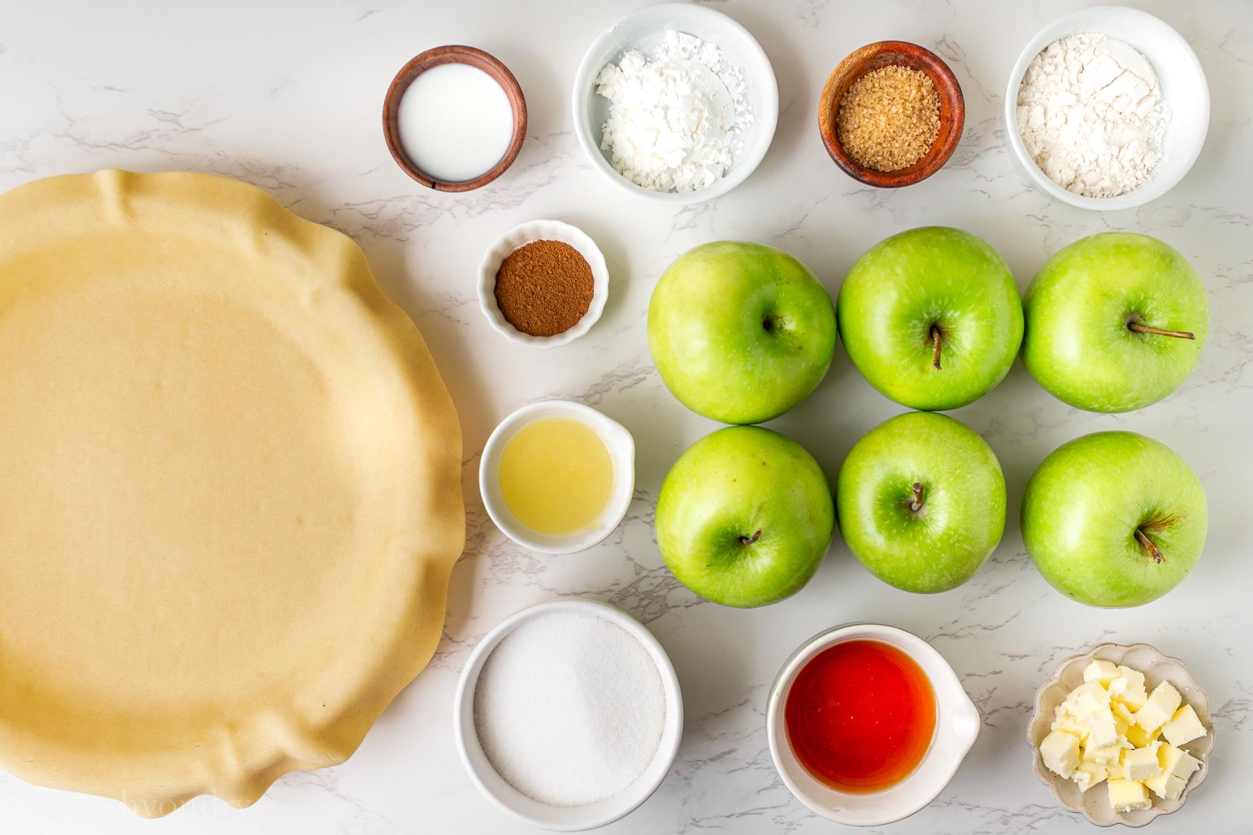 Ingredients for apple pie on white surface.