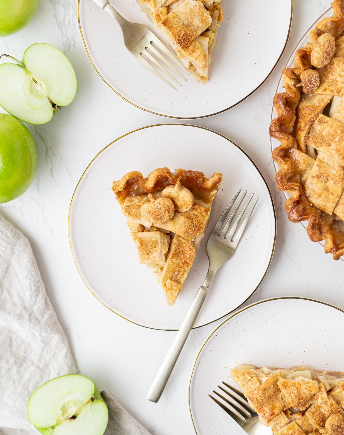 slice of homemade apple pie on white plate with top lattice crust.