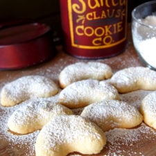 Crescent shaped cookies on a cutting board sprinkled with powdered sugar