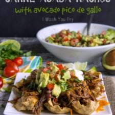 A plate of carne asada nachos topped with avocado pico de gallo