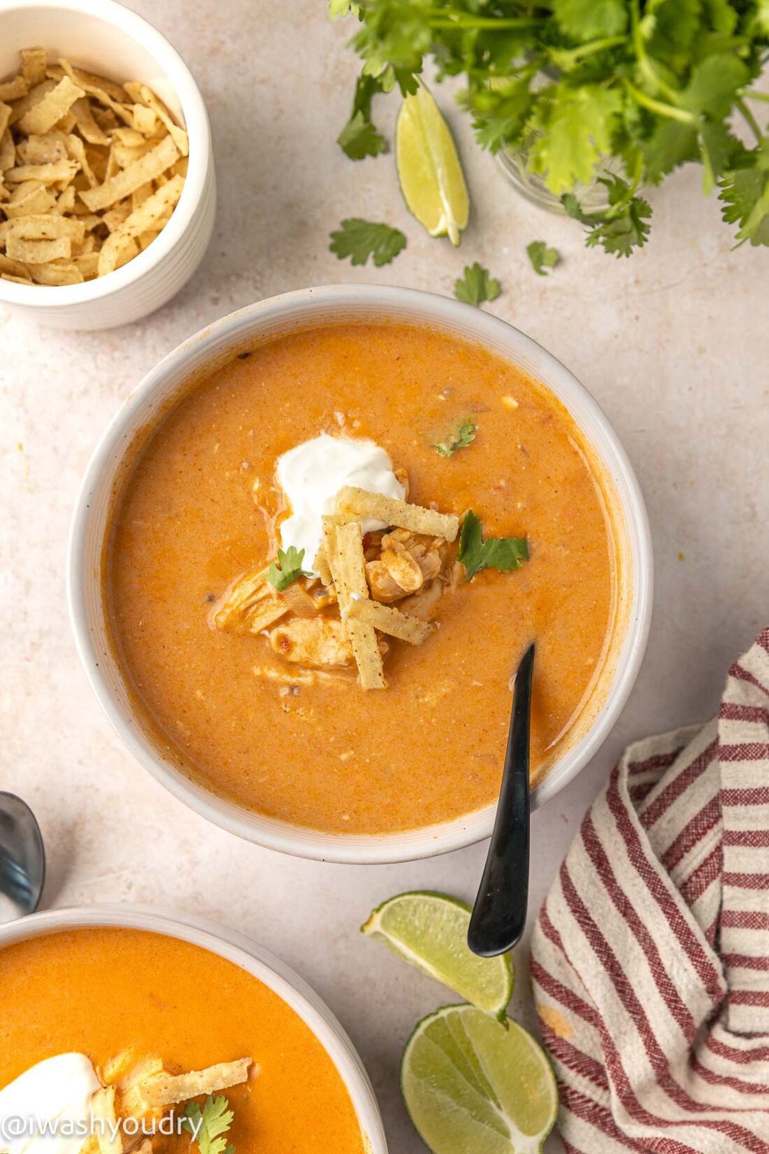 creamy chicken enchilada soup recipe with tortilla strips and sour cream on top.
