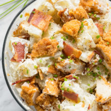 A close up of a bowl of potato salad with chicken and bacon