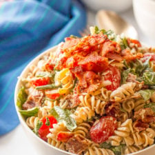 A bowl is filled with food, with pasta, bacon, and veggies