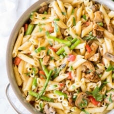 A pan of pasta, with chicken, asparagus and veggies