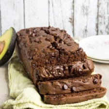 A loaf of chocolate avocado zucchini bread with chocolate chips and a few slices made from it