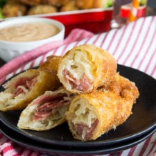 A plate of egg rolls cut in half stuffed with meat and cheese