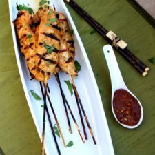 Grilled chicken tenders on skewers with a side of Spicy Peanut Dipping Sauce