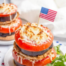 A plate of sandwich, with eggplant, tomato and mozzarella topped with a United States Flag toothpick decoration