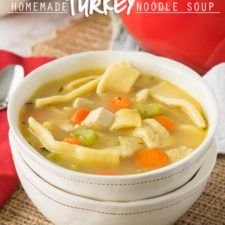 A bowl of soup, with noodle, turkey, carrots and celery