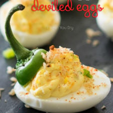 A close up of half a boiled egg topped with a creamed yolk and a jalapeño