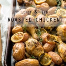 A close up of chicken on a pan, with baked lemons and potatoes