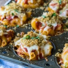 A close up of a muffin tin of food, with noodles and cheese