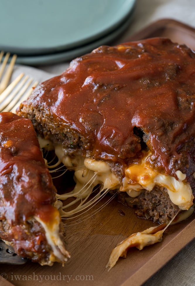 A close up of food, with meatloaf, cheese and sauce