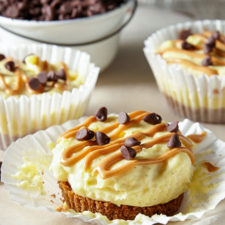 A close up of an unwrapped cupcake cheesecake topped with chocolate chips