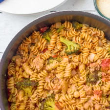 A pot of food, with pasta, sausage, broccoli and other veggies