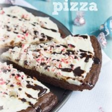 A close up of a Peppermint Brownie Pizza with a slice being removed.