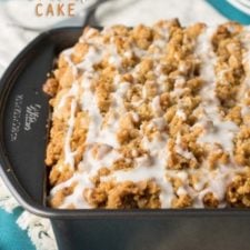 A close up of a bread pan of food, with a crumb topping and white icing