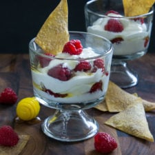 A glass dessert cup filled with Raspberry Greek Yogurt Parfait layered with fresh raspberries