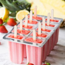 strawberry pineapple frozen popsicles in a mold on a table