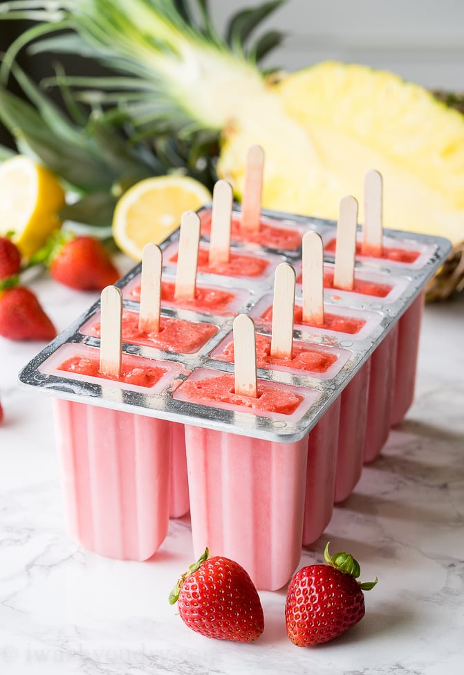 strawberry pineapple frozen popsicles in a mold on a table
