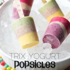 Four colorful layered Trix Yogurt Popsicles displayed on a tray of ice
