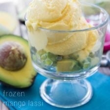 A glass dessert cup with avocado chunks topped with a couple scoops of Frozen Mango Lassi