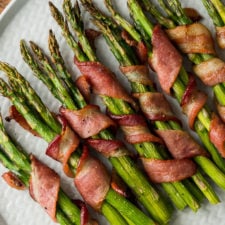 OMG! This Bacon Wrapped Asparagus Recipe is seriously so delicious! We served this easy side dish with steaks and mashed potatoes and it was a total hit!