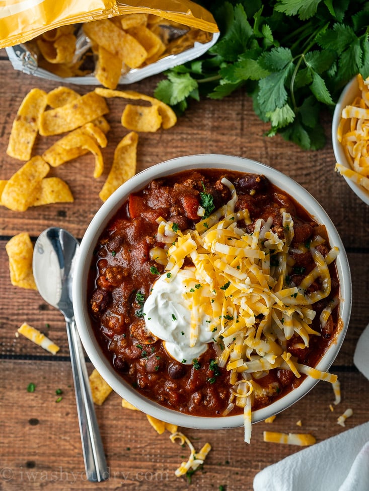 bowl of chili with spoon and sour cream on top. 