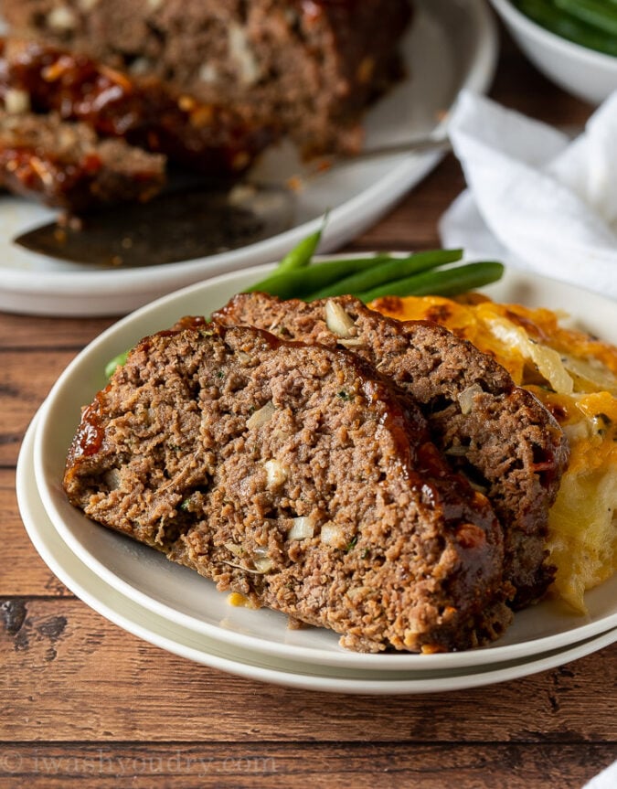 Sliced meatloaf on white plate with green beans