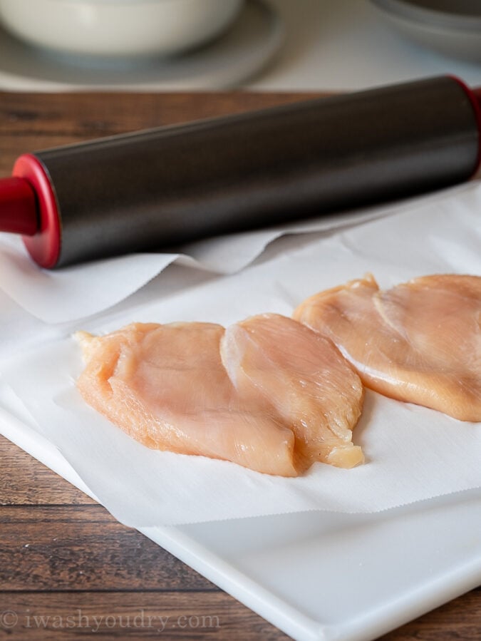 Chicken Breast on cutting board with rolling pin on parchment paper