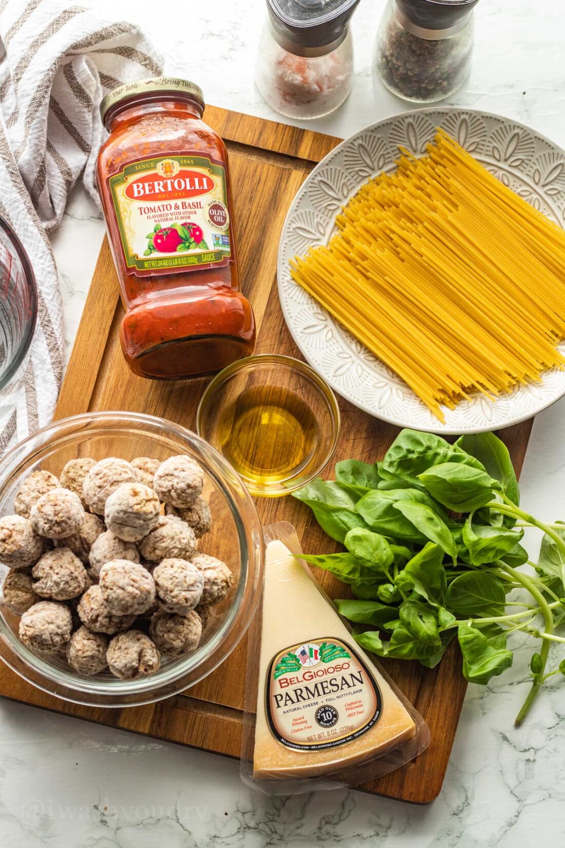 Ingredients for instant pot spaghetti and meatballs on wood cutting board. 