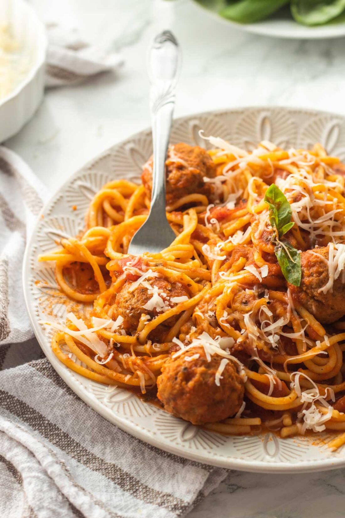 Cooked spaghetti and meatballs on white plate with fork 